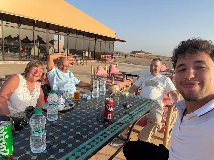 Un groupe de voyageurs réuni autour d’une table sur une terrasse de camp