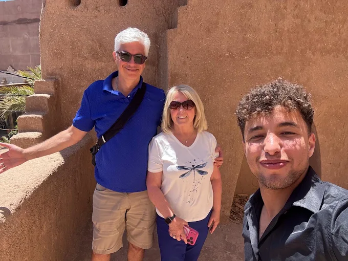 Trois voyageurs devant des murs en terre au Maroc